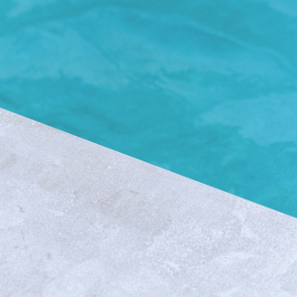 The edge of a pool with crystal clear blue water.